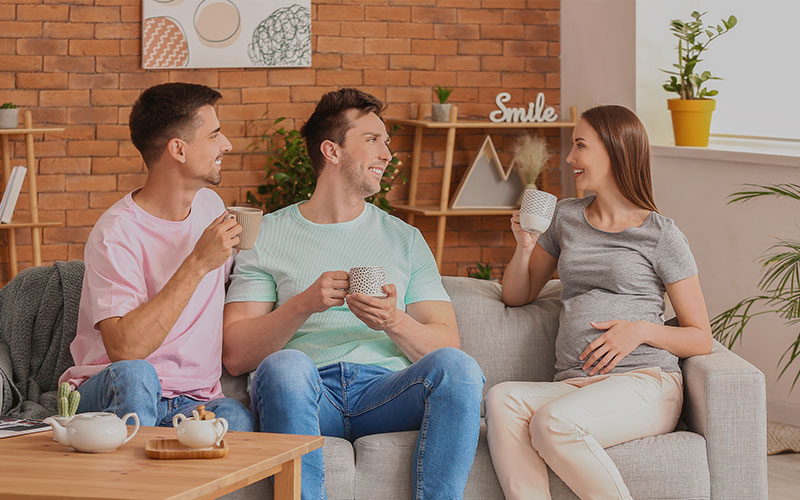 image of gay couple talking to a surrogate woman carrying their baby